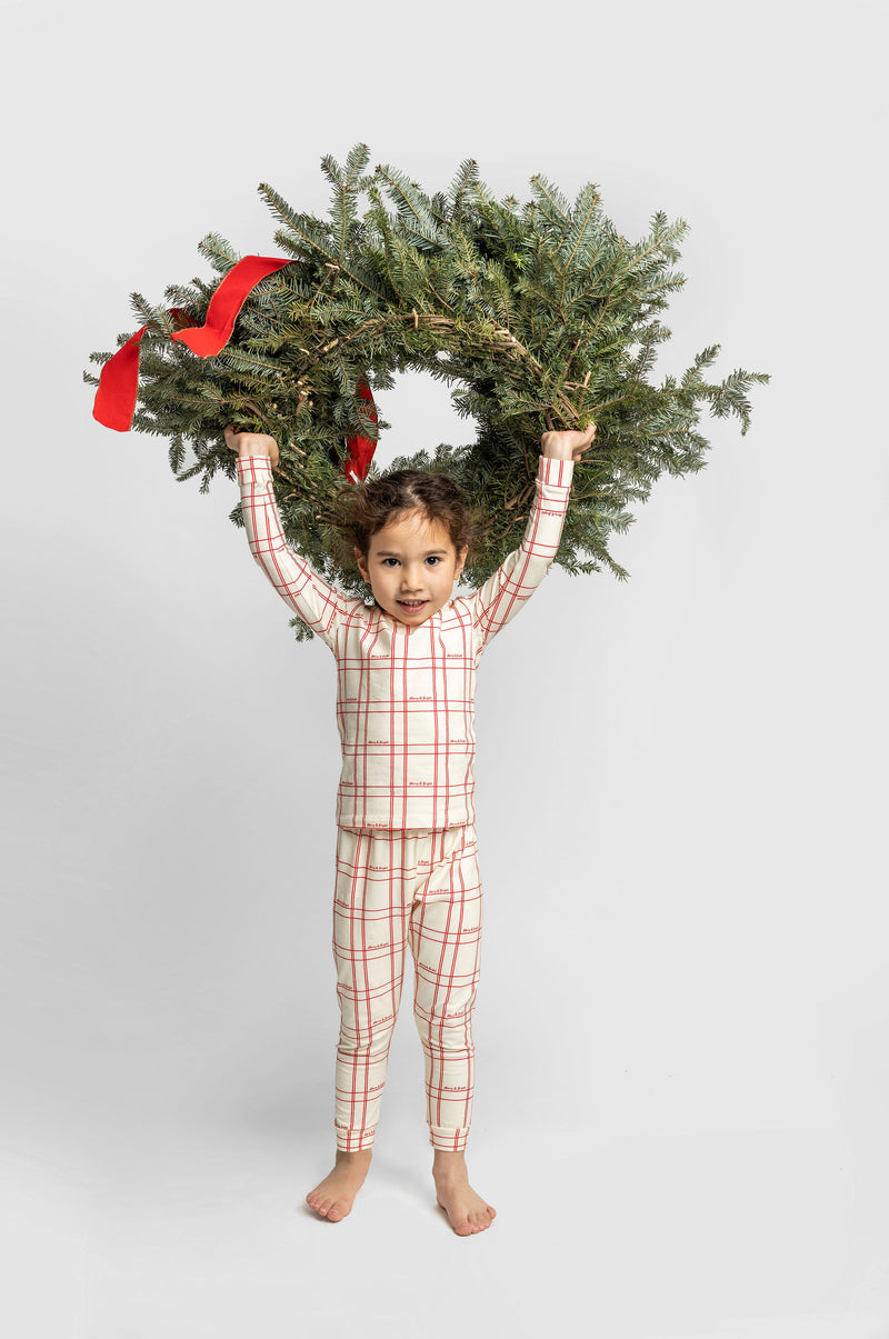 Holiday Plaid matching two-piece toddlers pajama on girl with wreath